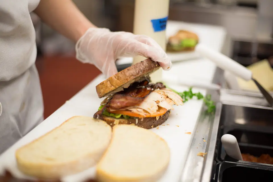 Gloved hands assembling sandwiches in a catering kitchen
