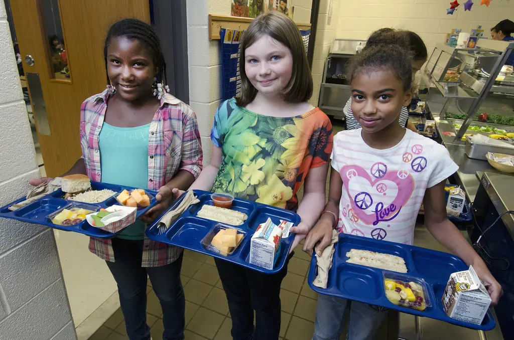 Three students holding their school lunch trays